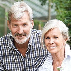 Older man and woman with healthy smiles thanks to restorative dentistry