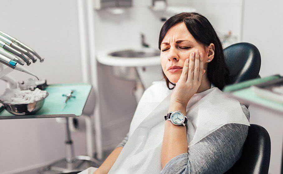 Woman in need of emergency dentistry holding cheek