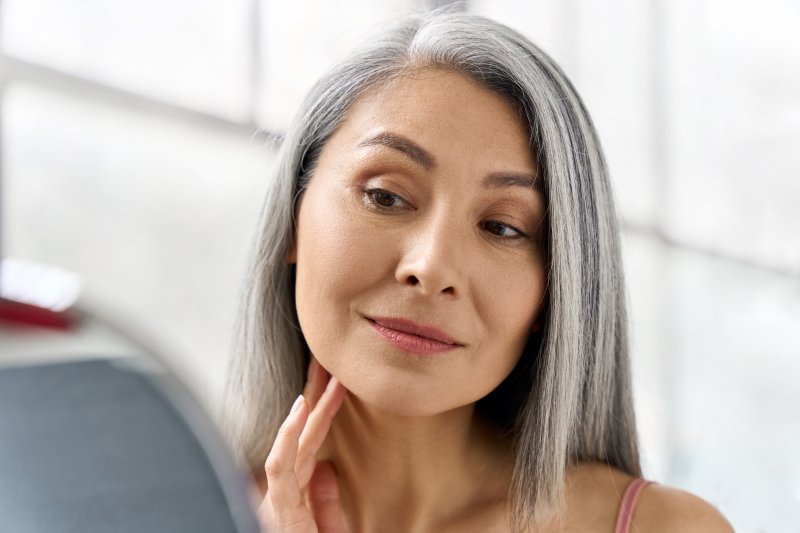 Woman looking at her face in the mirror after BOTOX